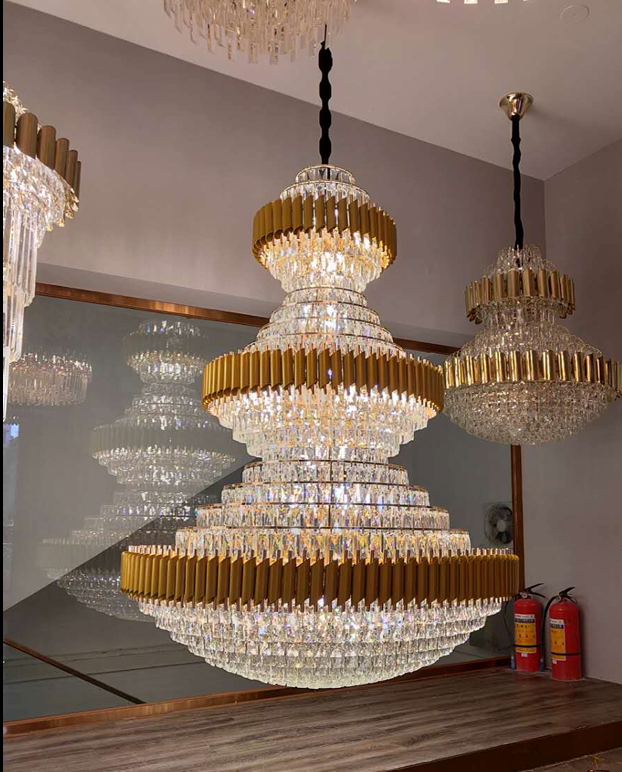 A 3-tier gold chandelier with LED lights, hanging from the ceiling in a room with a mirrored wall and a wooden counter.