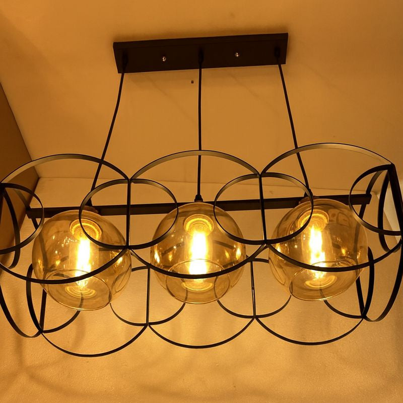 Modern chandelier with three illuminated glass bulbs against a neutral background