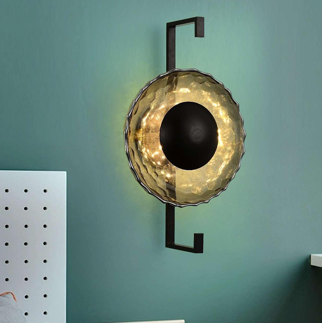  LED light fixture with a metallic saucer-shaped top and a black metal frame, mounted on a green wall in a cozy room setting.
