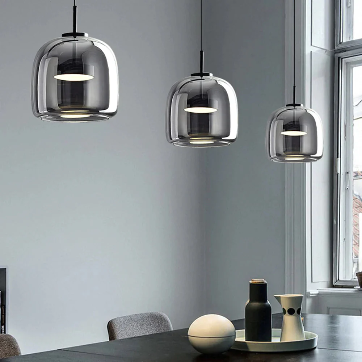 Modern pendant lights hanging above a dining table with a neutral background