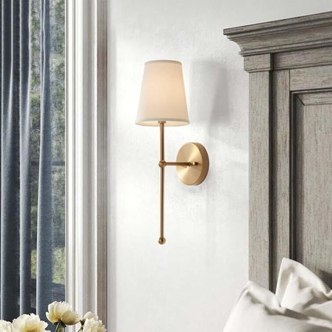 Wall sconce on a white wall next to a window with curtains and a bed.