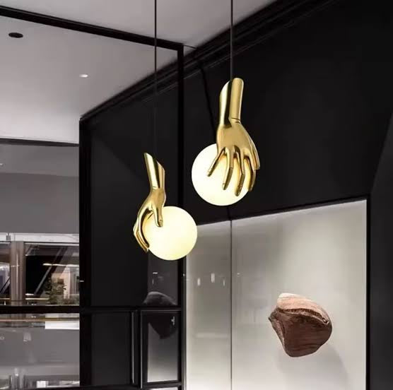 Gold hand-shaped pendant lights hanging in a modern interior setting.