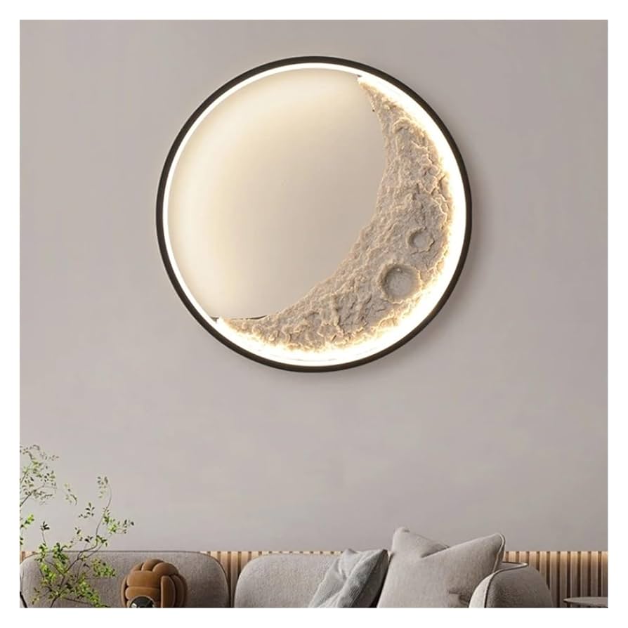Round wall mirror with moon design on a gray wall above a sofa.