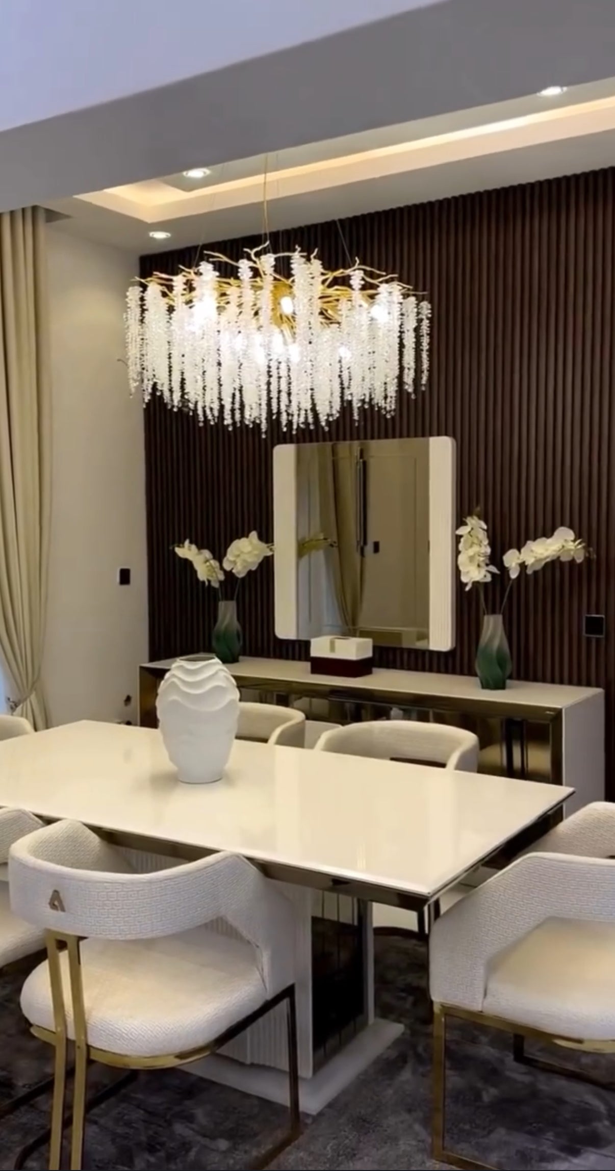 Modern dining room with a chandelier, table, chairs, and decorative elements.