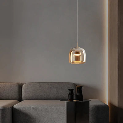 Modern pendant light hanging above a gray sofa in a minimalistic room.