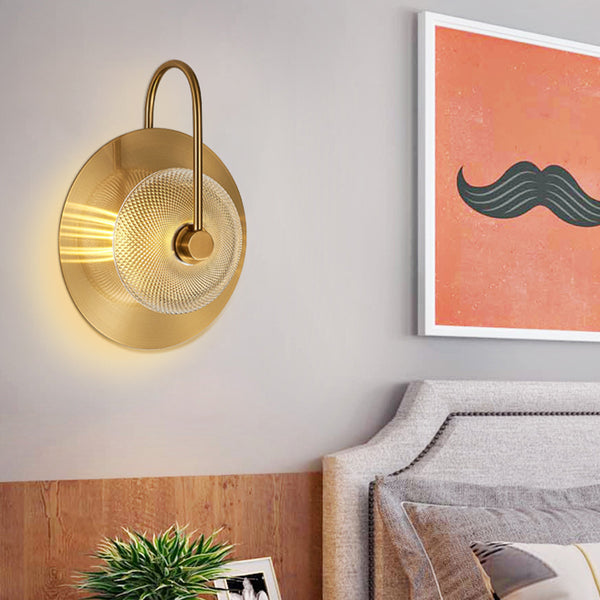 Gold wall sconce and framed artwork with a mustache on a wall above a bed.