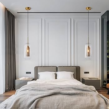 Modern bedroom with gray bed, pendant lights, and white walls.