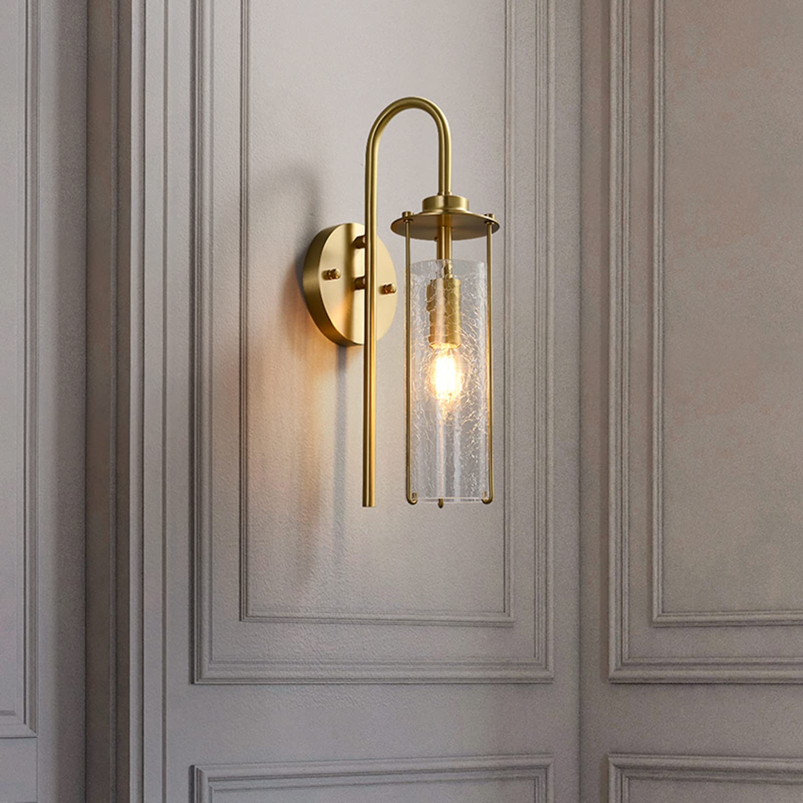 Gold wall sconce with glass shade on a paneled wall
