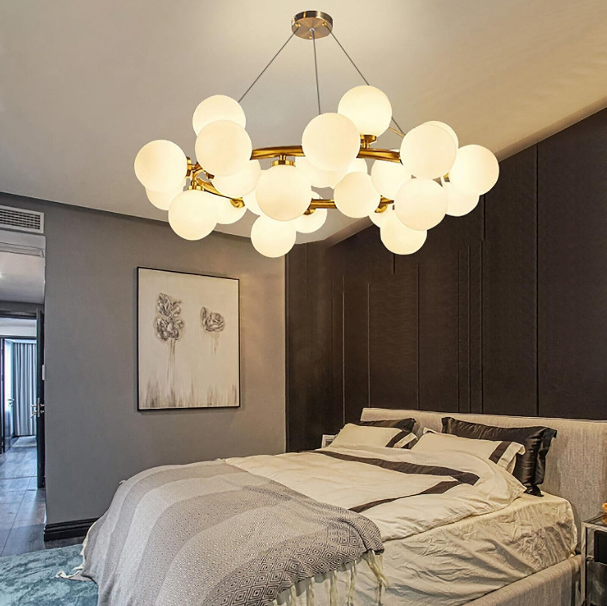 Modern chandelier in a bedroom with a bed and wall art.