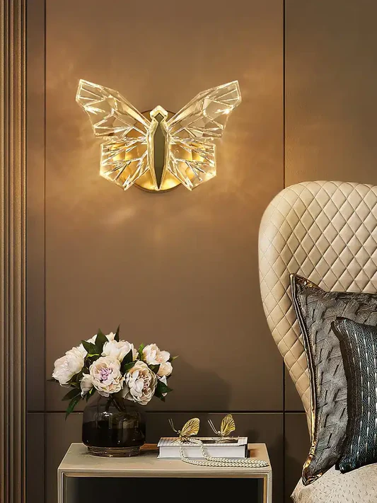 Butterfly-shaped wall light fixture on a brown wall with a decorative table and chair.