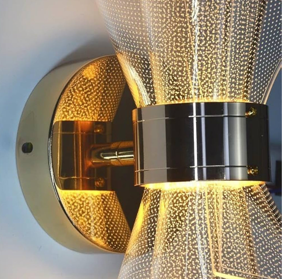 Decorative wall light fixture with gold and black design on a neutral background