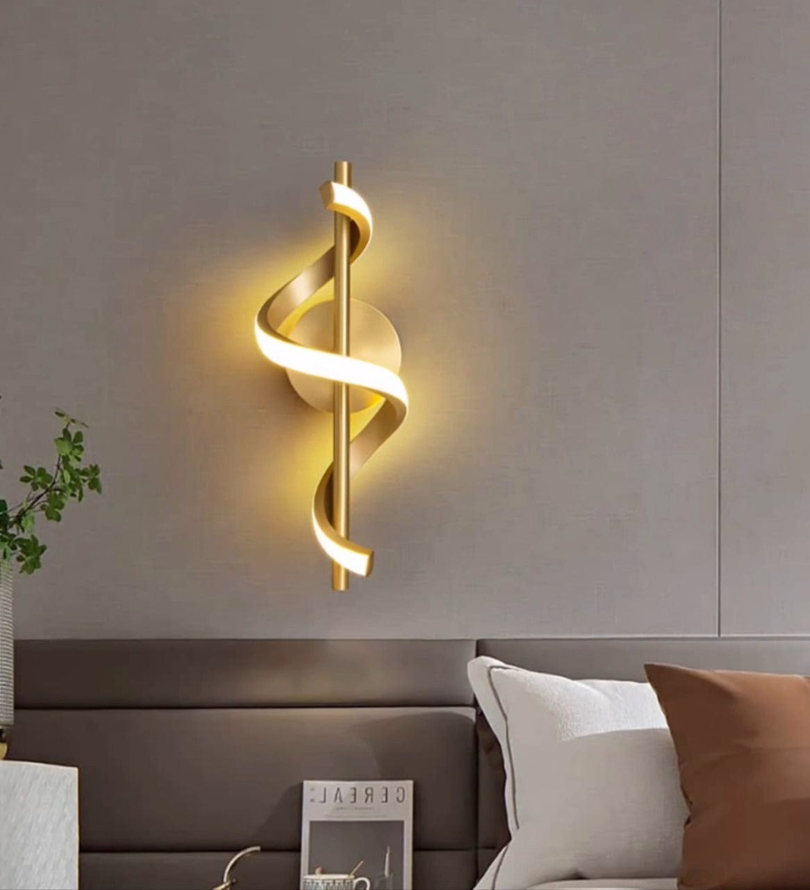 Modern wall sconce with a gold spiral design on a neutral wall.