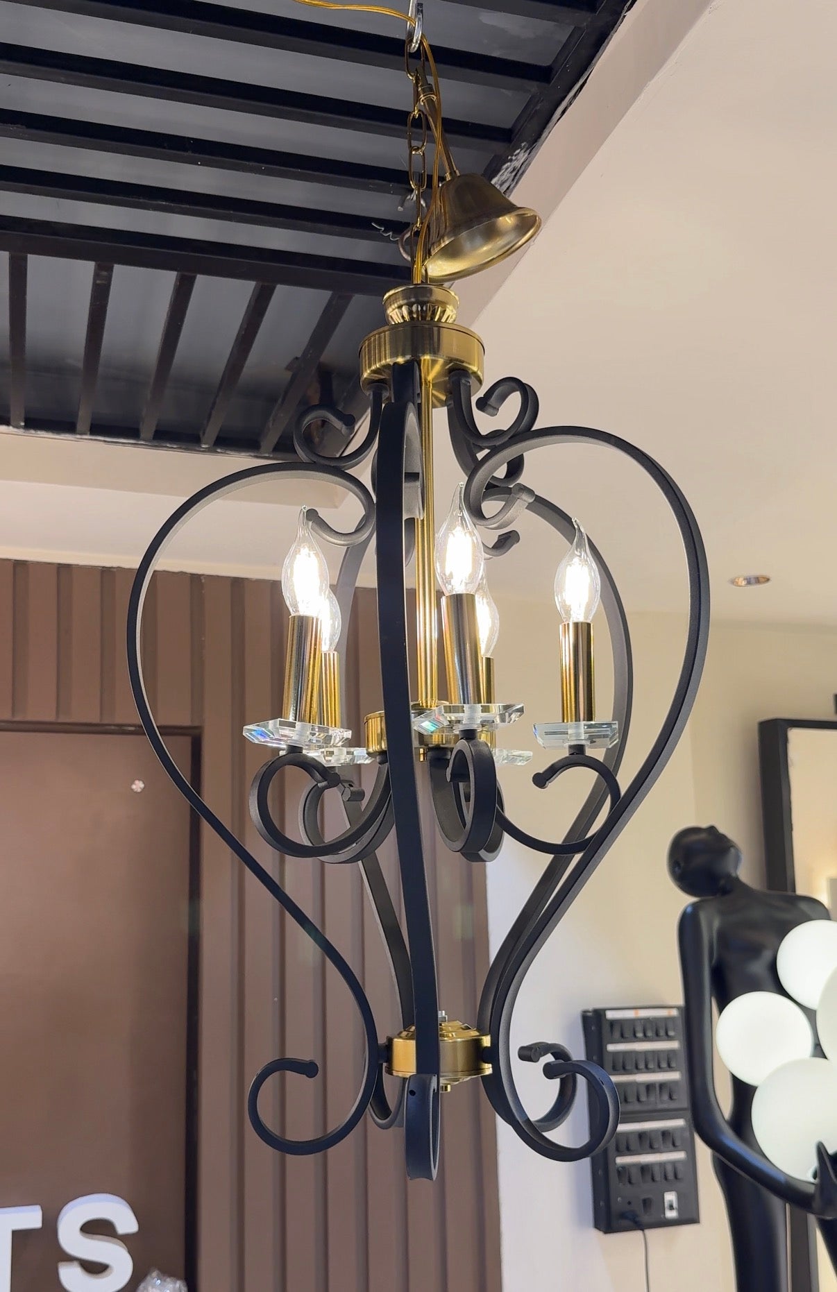 Decorative chandelier with black and gold design hanging from a ceiling.