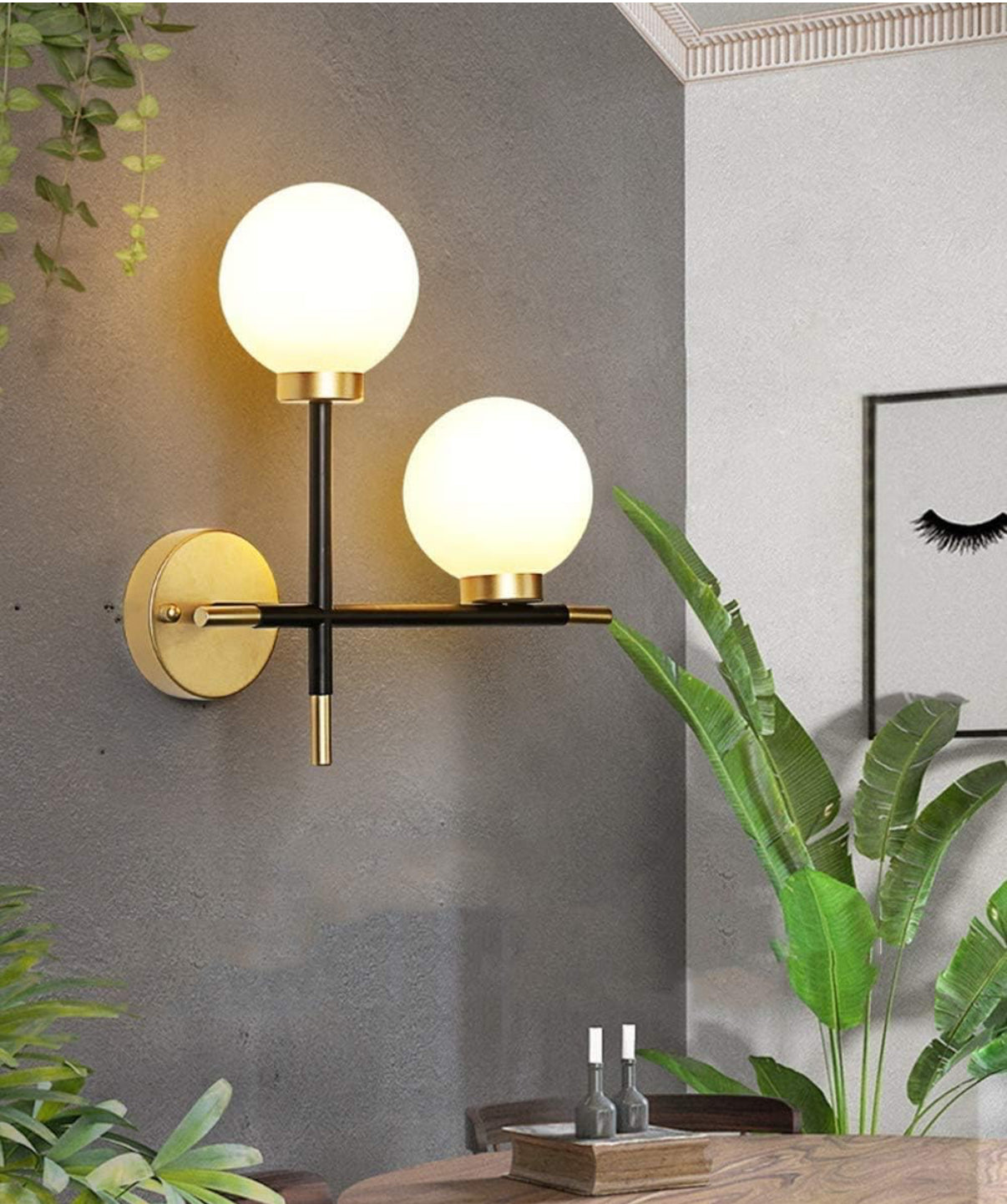 Modern wall sconce with two globe lights in a room with plants and a framed picture.