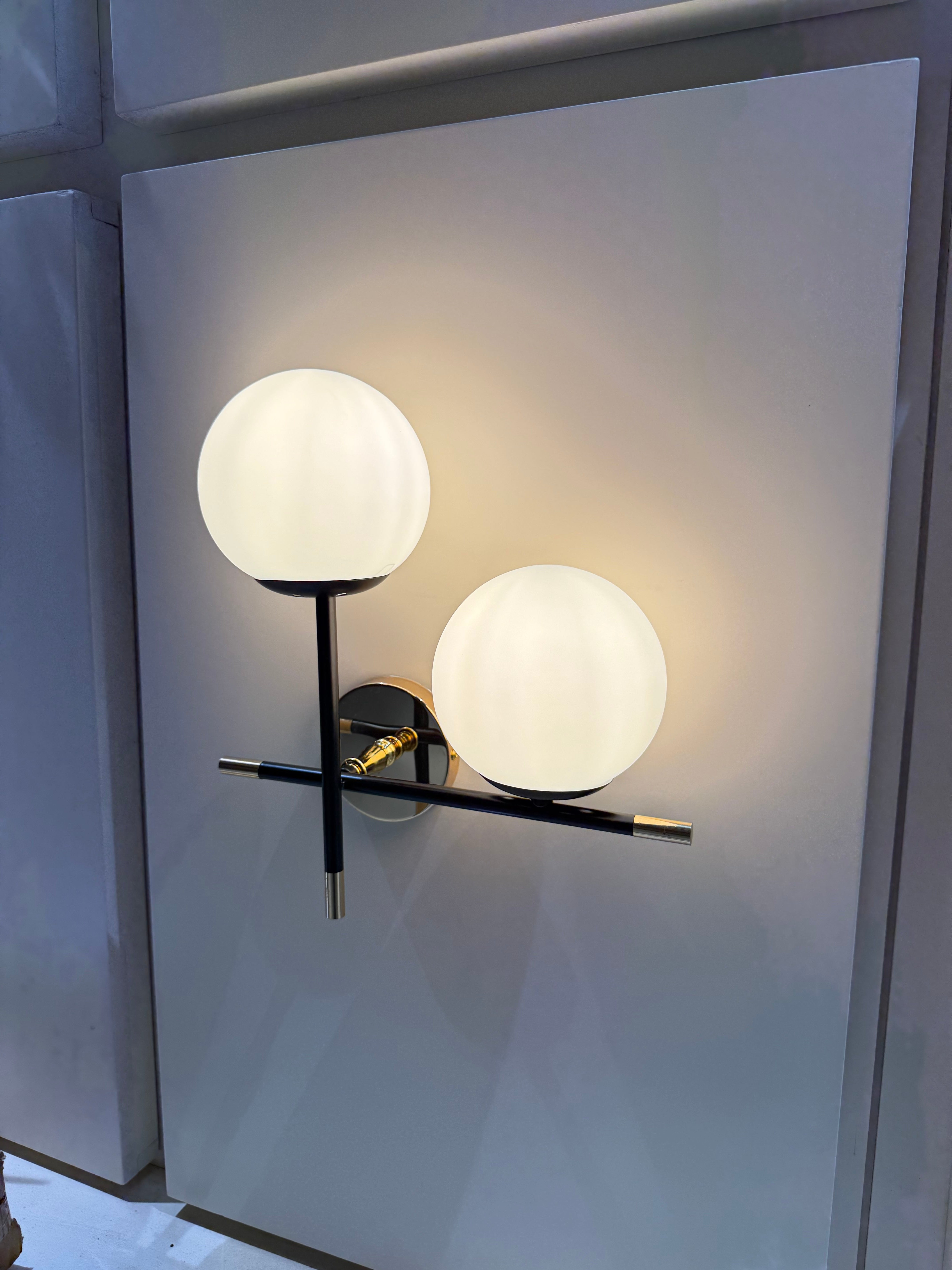 Modern wall-mounted light fixture with two round glass shades on a neutral background