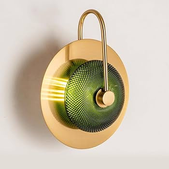 Decorative wall light fixture with gold finish and green glass shade on a white background