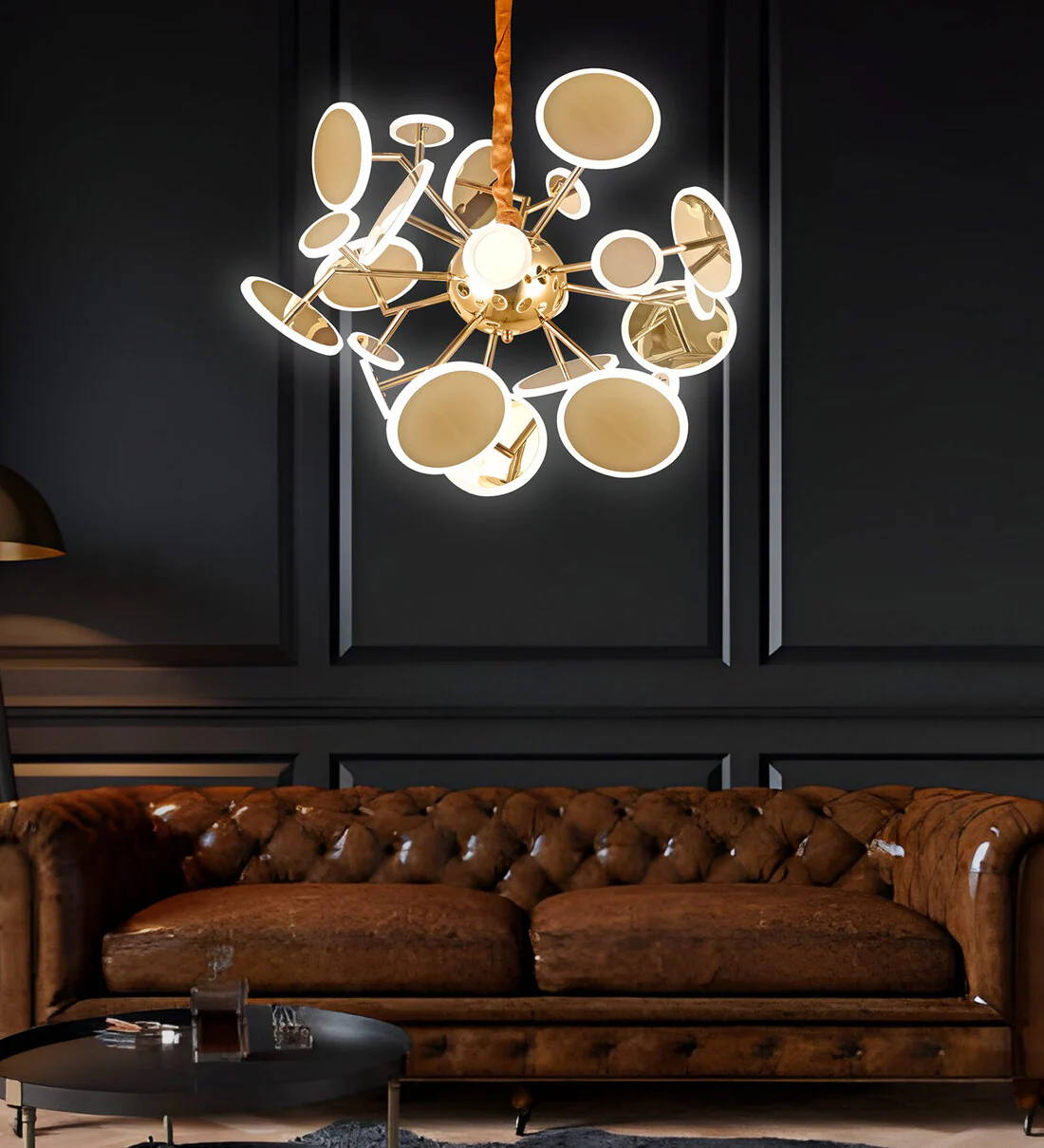 Modern chandelier hanging above a brown leather sofa in a darkly paneled room.