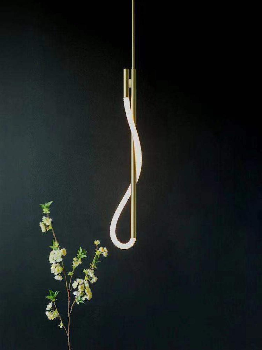 Modern pendant light with a gold finish on a dark background