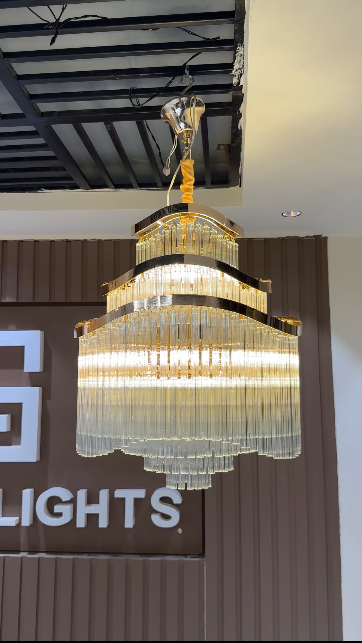 Chandelier hanging from the ceiling with a brand name visible in the background