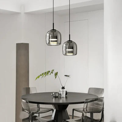 Modern dining area with round table and chairs under glass pendant lights.