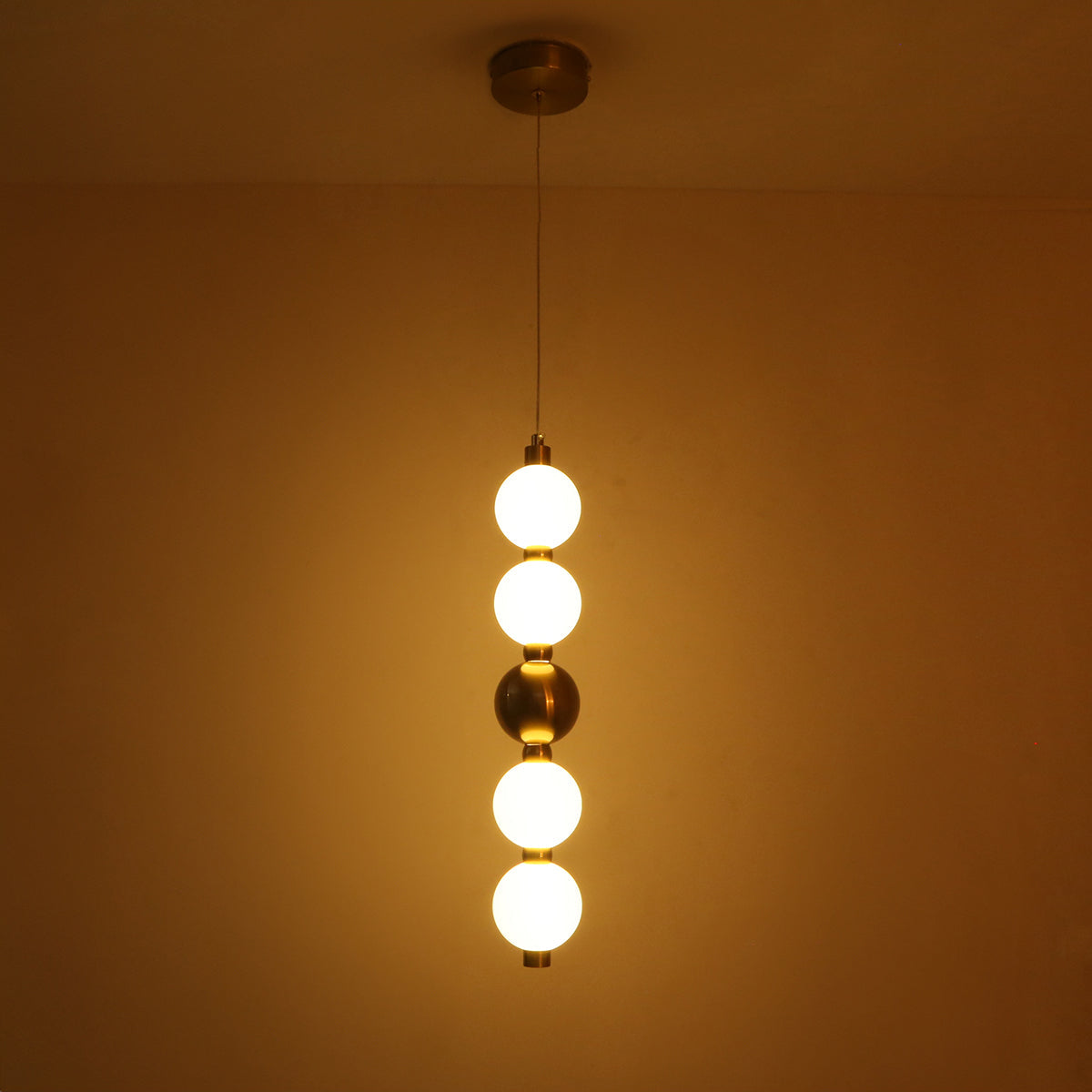 Pendant light with four round bulbs hanging against a beige wall.