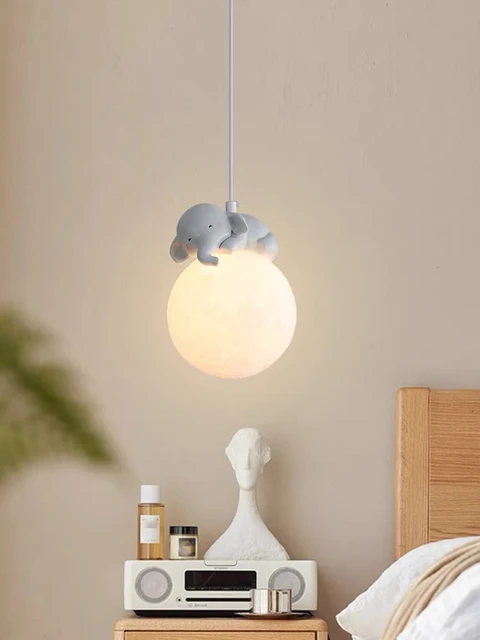 Pendant light with elephant design on a nightstand against a beige wall.
