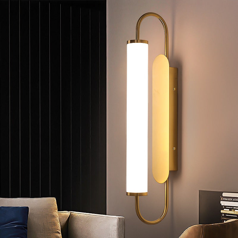 Modern wall lamp with gold finish and white shade in a living room setting.
