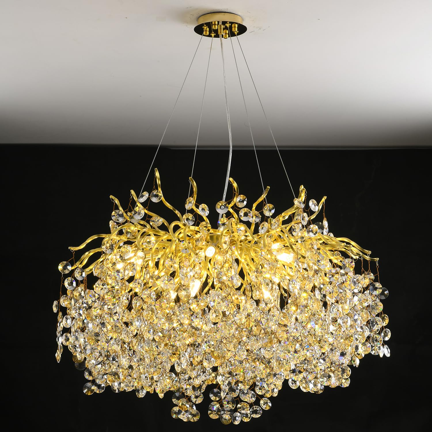 Gold and crystal chandelier hanging from the ceiling against a black background