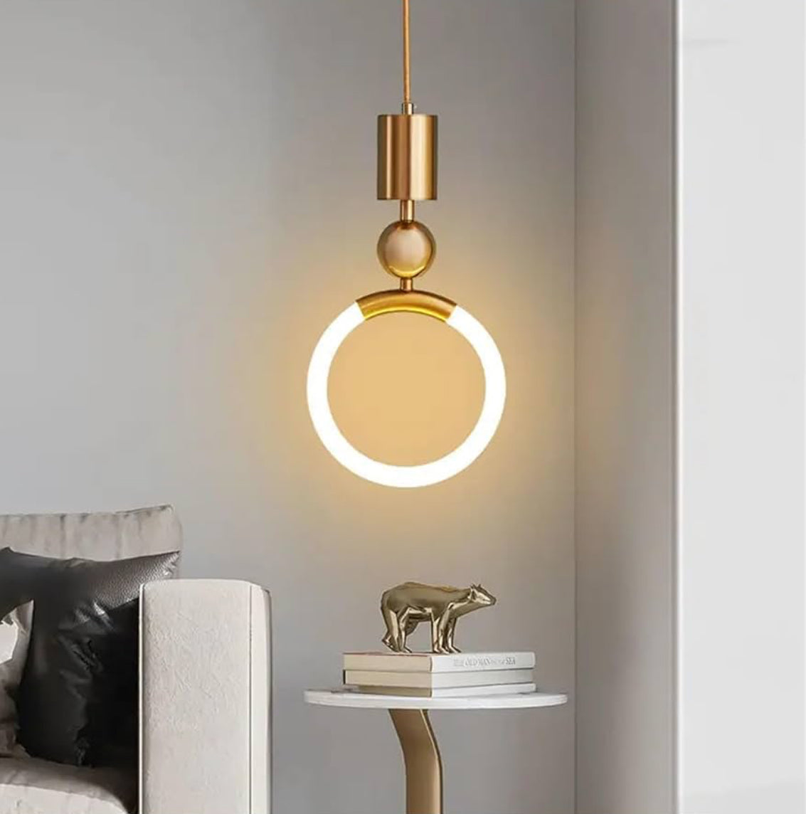 Modern pendant light fixture in a living room setting with a sofa and decorative items.