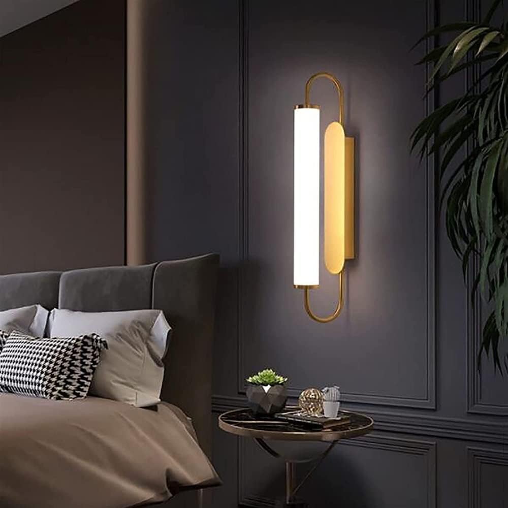 Modern wall sconce in a bedroom setting with a bed and decorative items.