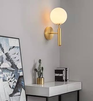 Modern wall lamp on a gray wall above a desk with decor items.