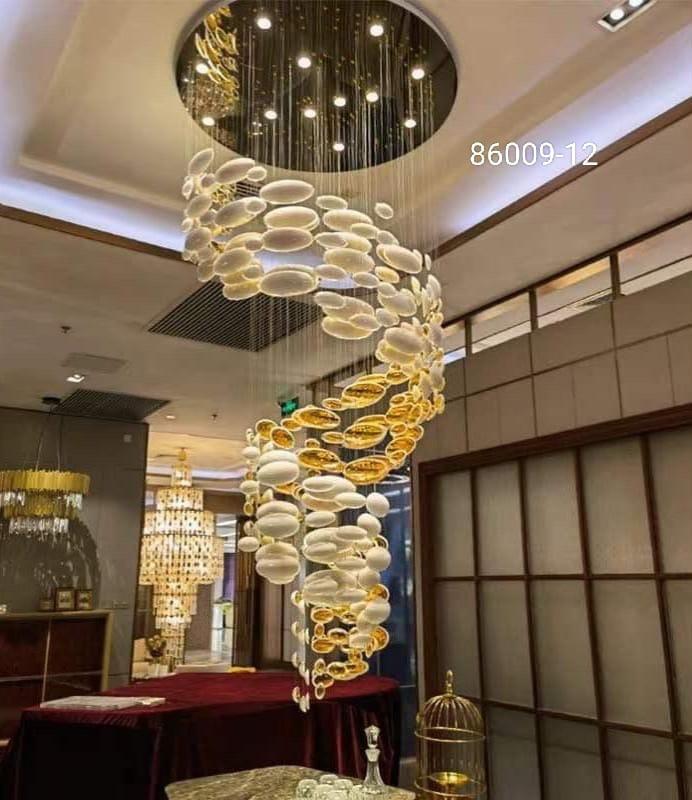 A gold-colored metal chandelier with a double-height design, featuring a series of suspended oval and round light fixtures.