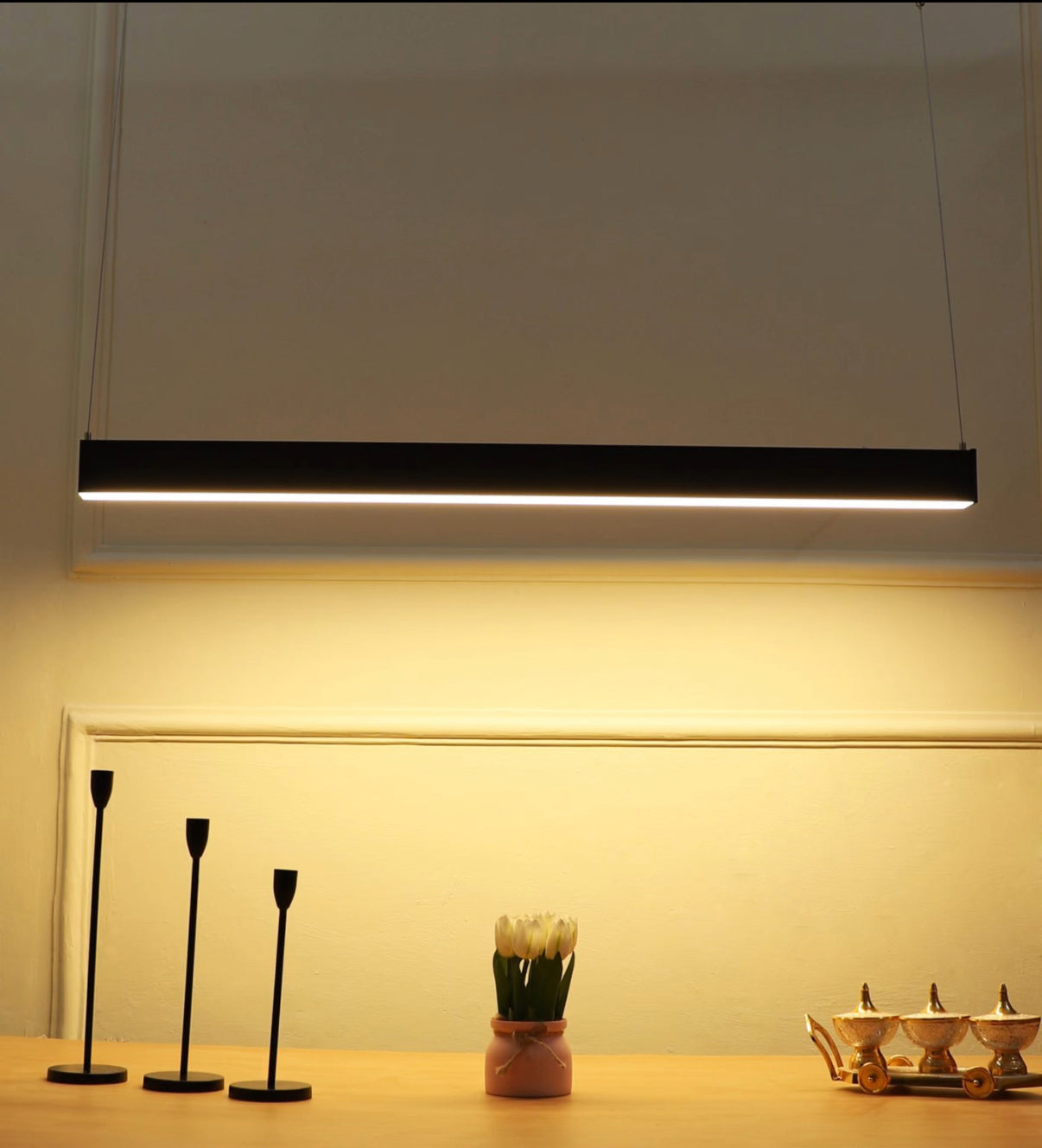 Modern pendant light fixture hanging above a table with decorative items.