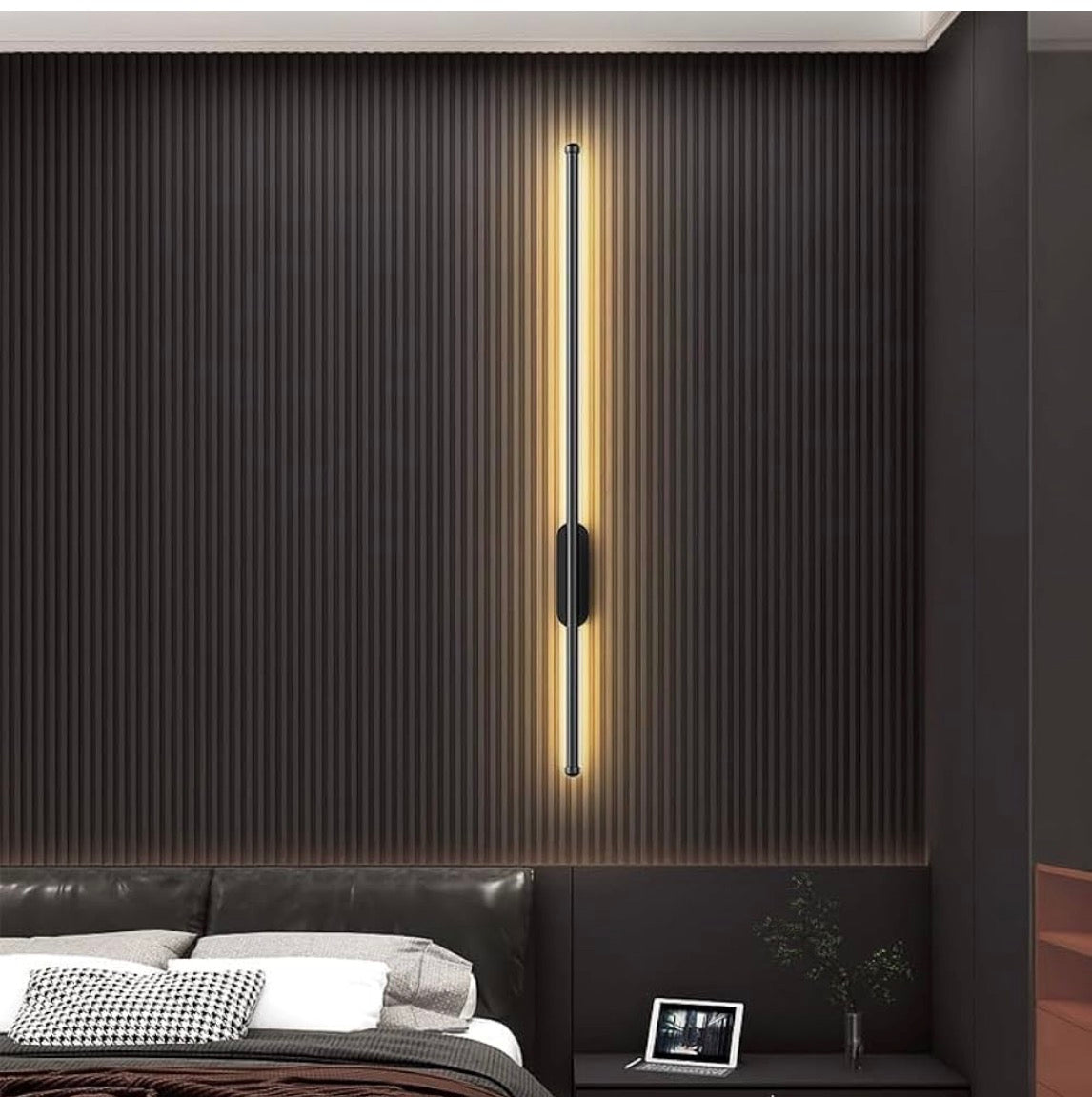 Modern wall-mounted light fixture on a textured wall above a bed in a bedroom.