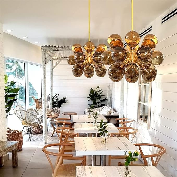 Modern dining room with a large, decorative chandelier hanging above tables and chairs.