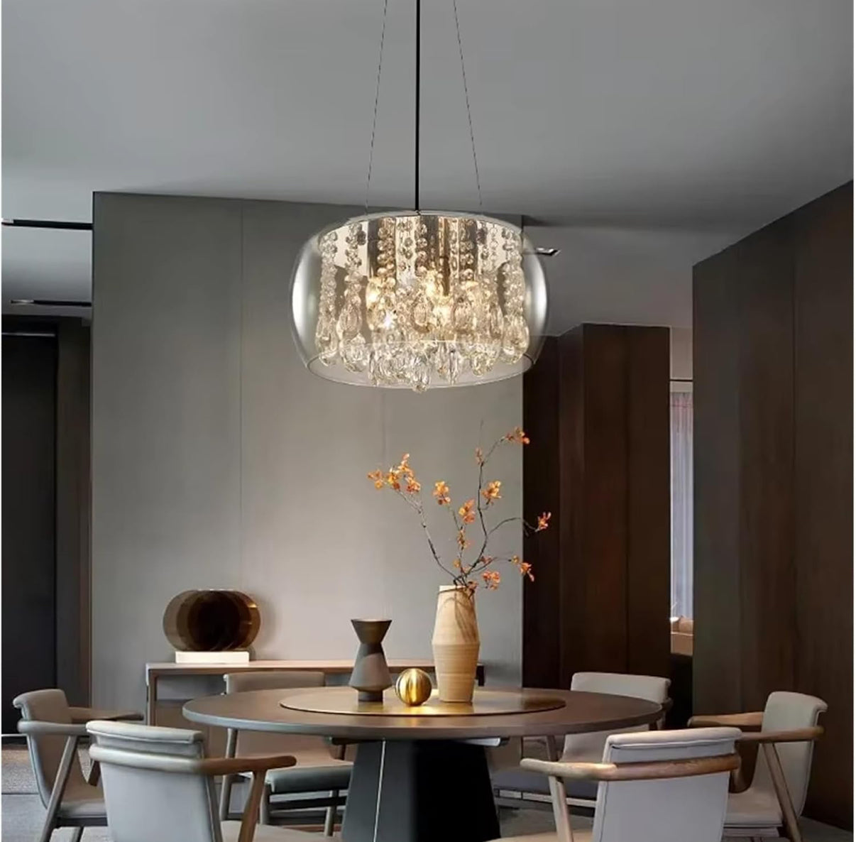 Modern dining room with a crystal chandelier, round table, and chairs.