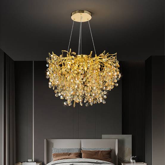Gold chandelier hanging above a bed in a dark room