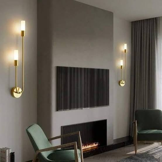 Modern living room with gold wall sconces, a television, and a fireplace.
