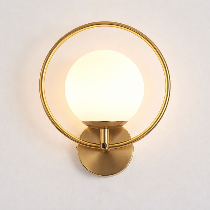Gold wall sconce with a white bulb on a light gray background
