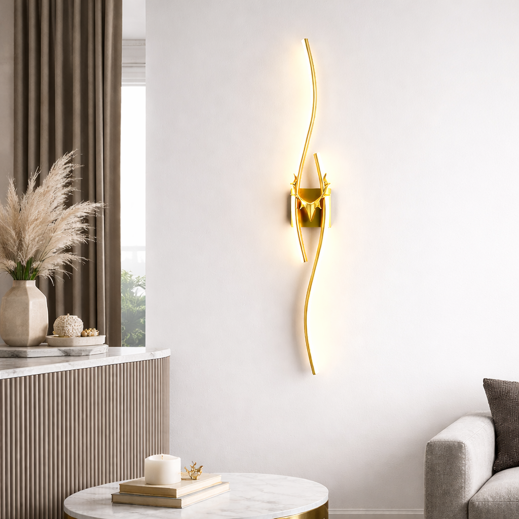 Modern wall lamp with gold finish on a white wall, next to a window with curtains and a side table.