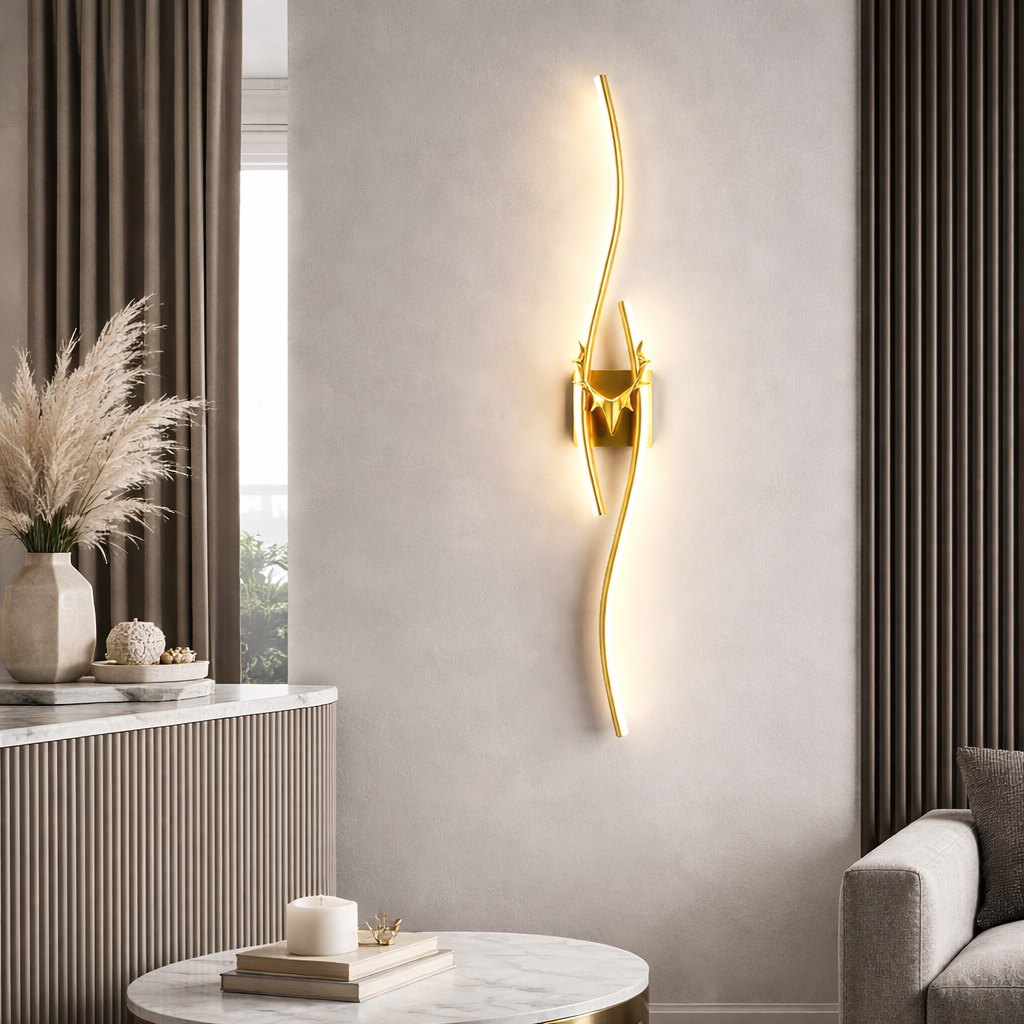 Modern wall lamp with gold finish on a gray wall, next to a window and decorative items.