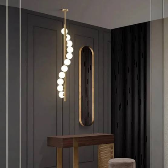 Modern pendant light fixture hanging in a stylish interior setting with a console table and decorative elements.