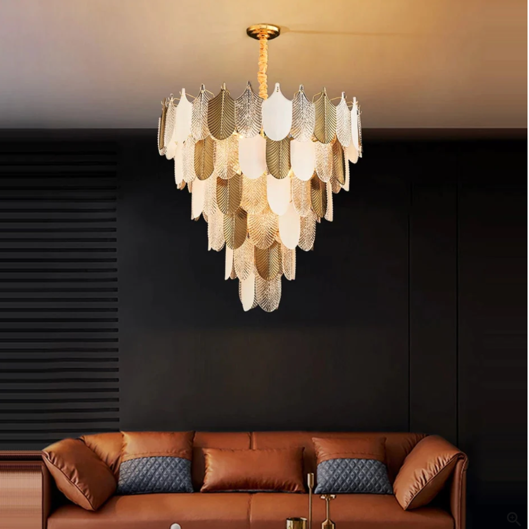 Chandelier hanging above a brown leather sofa in a dimly lit room.