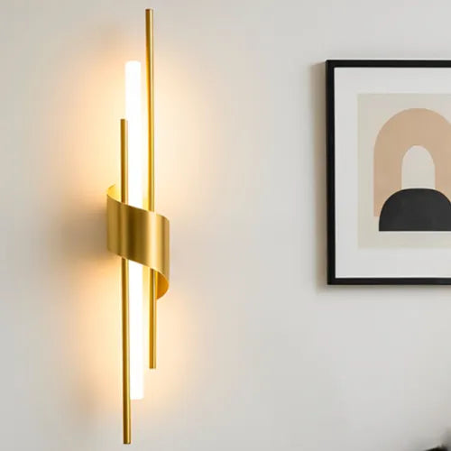 Gold wall sconce on a light gray wall with a framed abstract art piece.