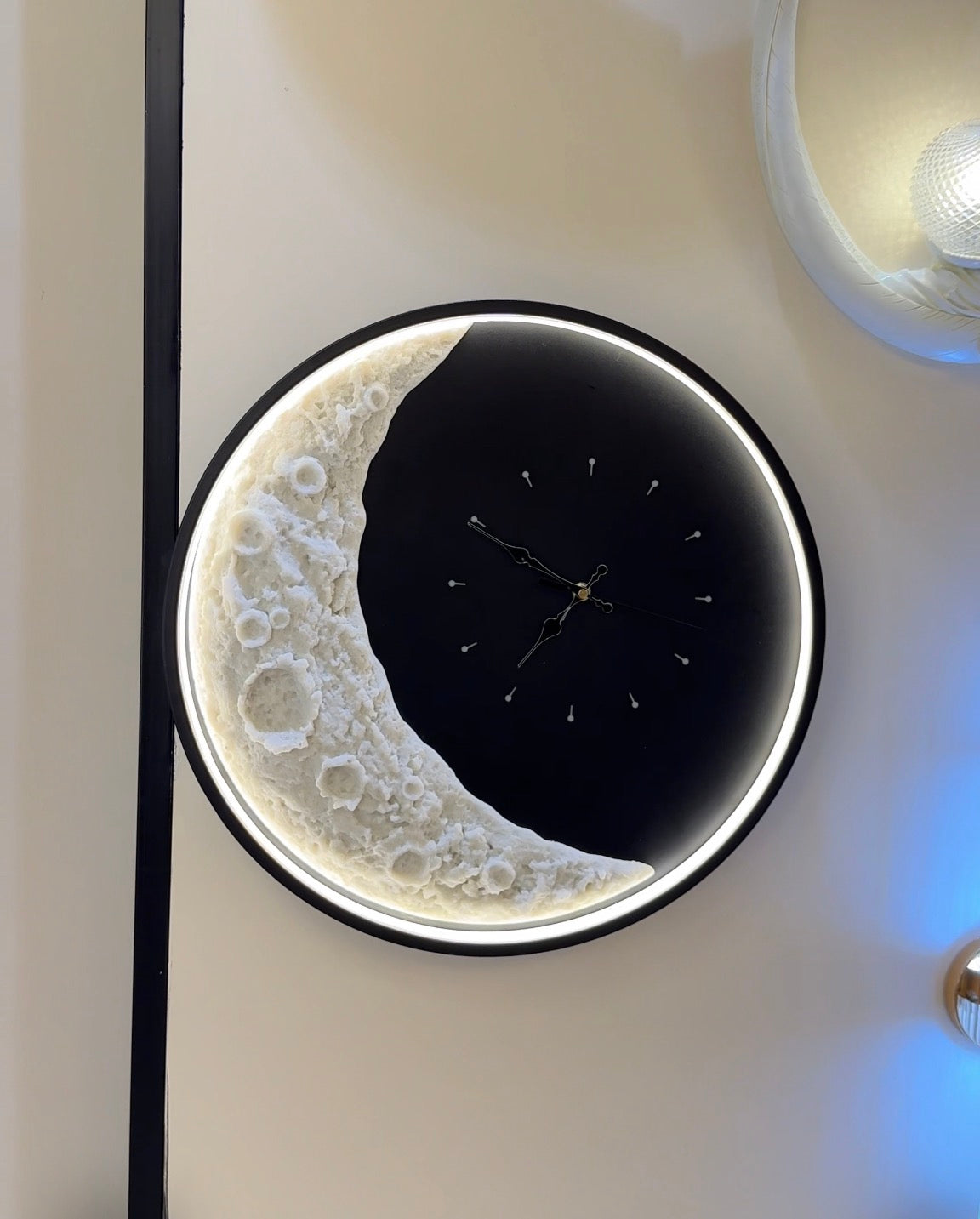 Decorative wall clock with moon and star design on a light-colored wall.