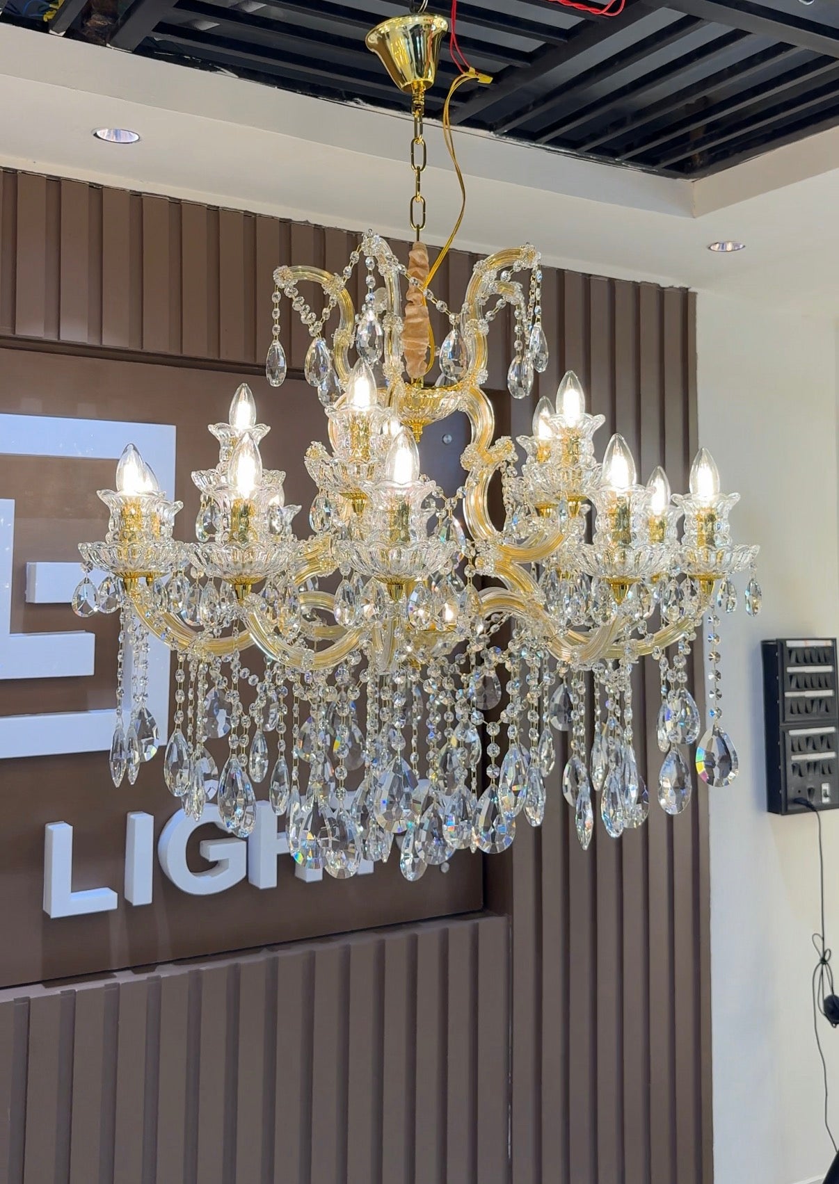 Gold chandelier with crystal accents in a showroom setting.
