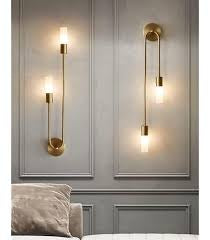 Wall-mounted lamps on a gray wall with a light-colored sofa in the foreground.