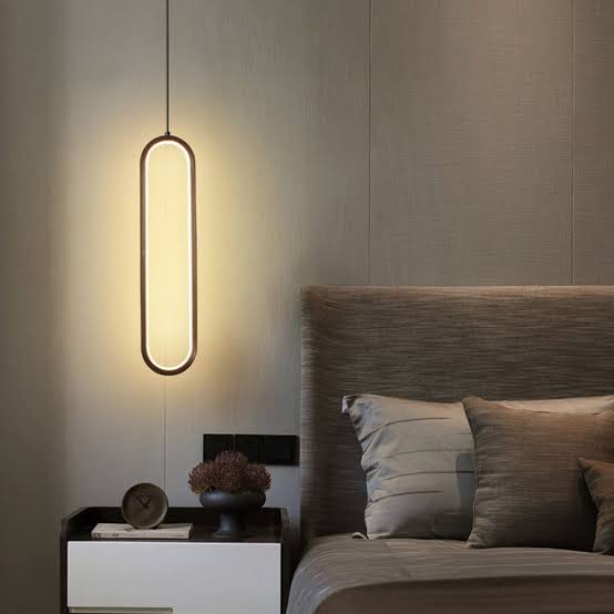 Modern pendant light hanging above a bed in a bedroom setting.