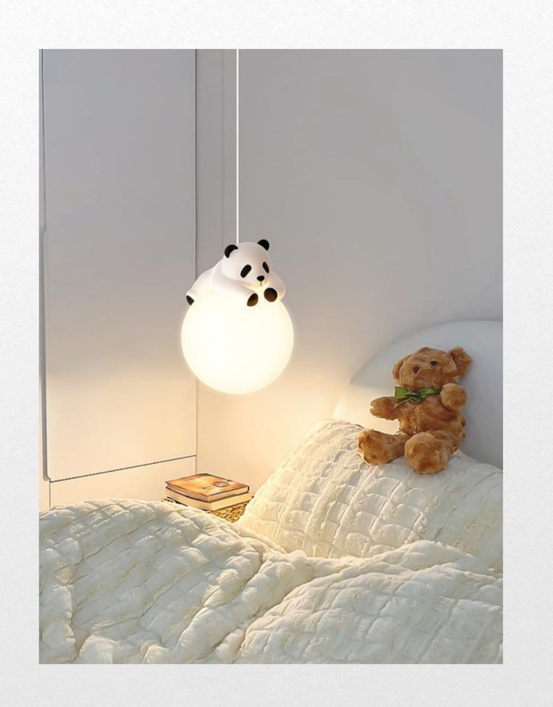 Panda-shaped lamp hanging above a bed with a teddy bear