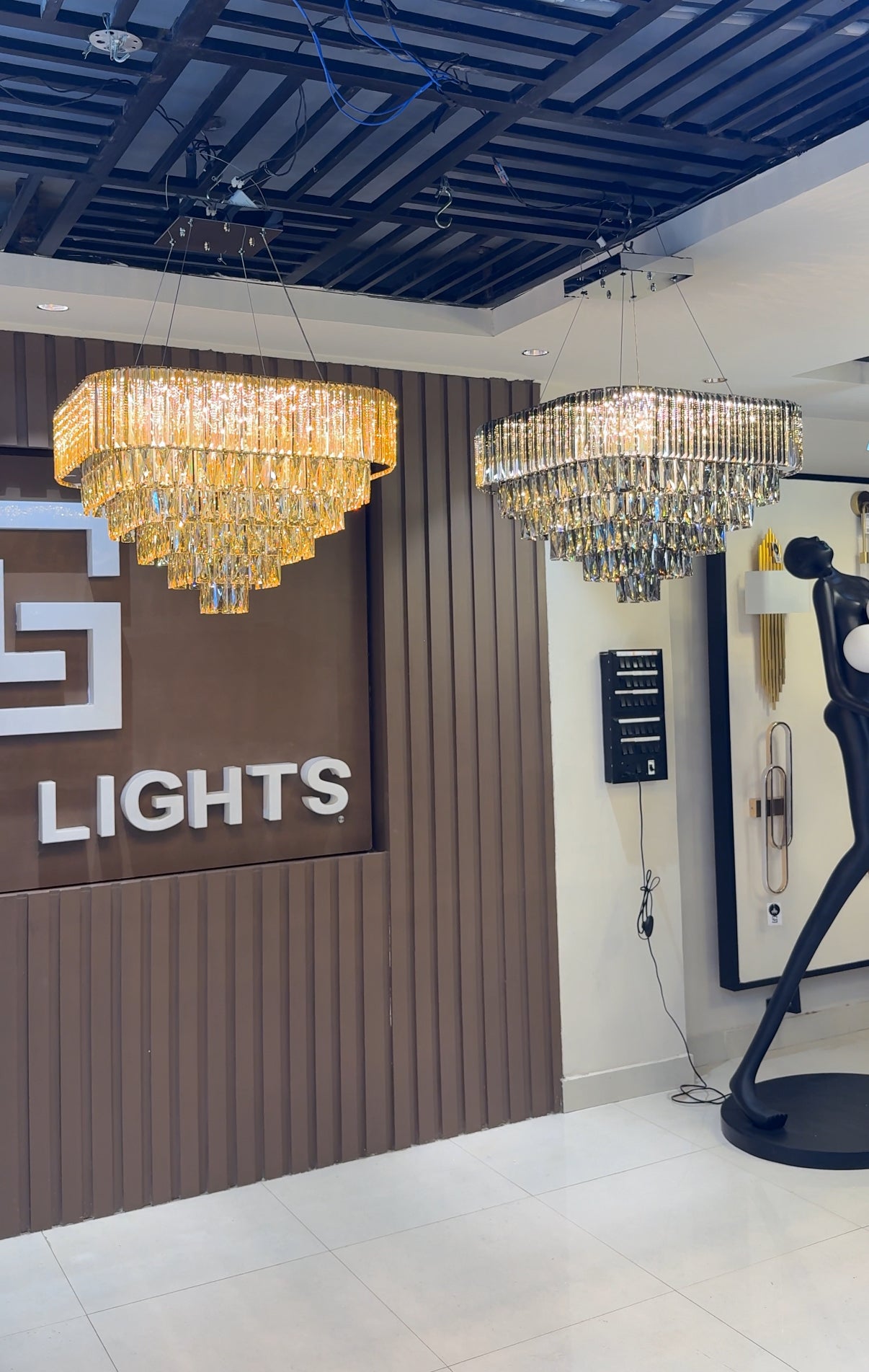 Two chandeliers hanging from a ceiling with a 'LIGHTS' sign in the background.